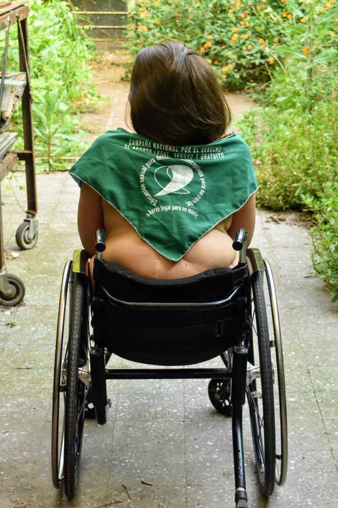 Milagros Shaw en su silla de ruedas con la espalda descubierta y el pañuelo verde en representación al aborto legal, seguro y gratuito. 