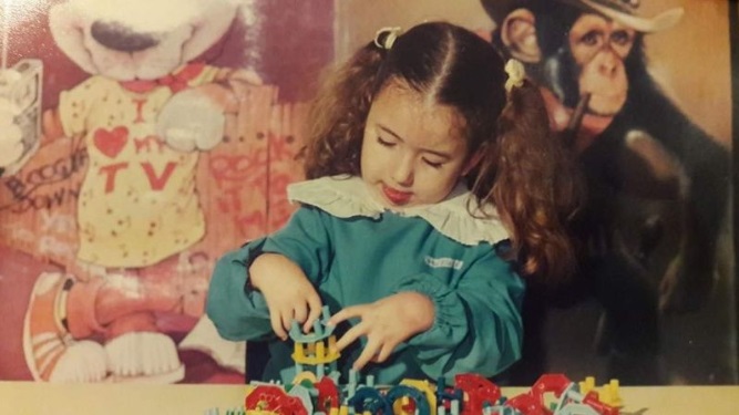 Daniela Aza de pequeña jugando sobre una mesa con sus juguetes