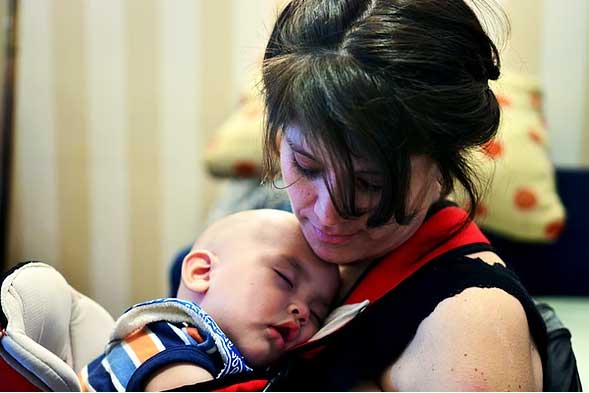 Anabella Mazzini sostiene en sus brazos a sus bebe, que duerme recostado contra su pecho