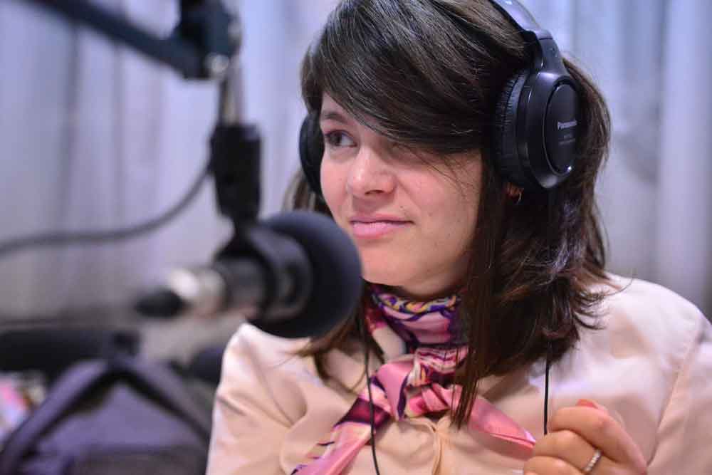 Anabella Mazzini con auriculares frente al micrófono en una radio 