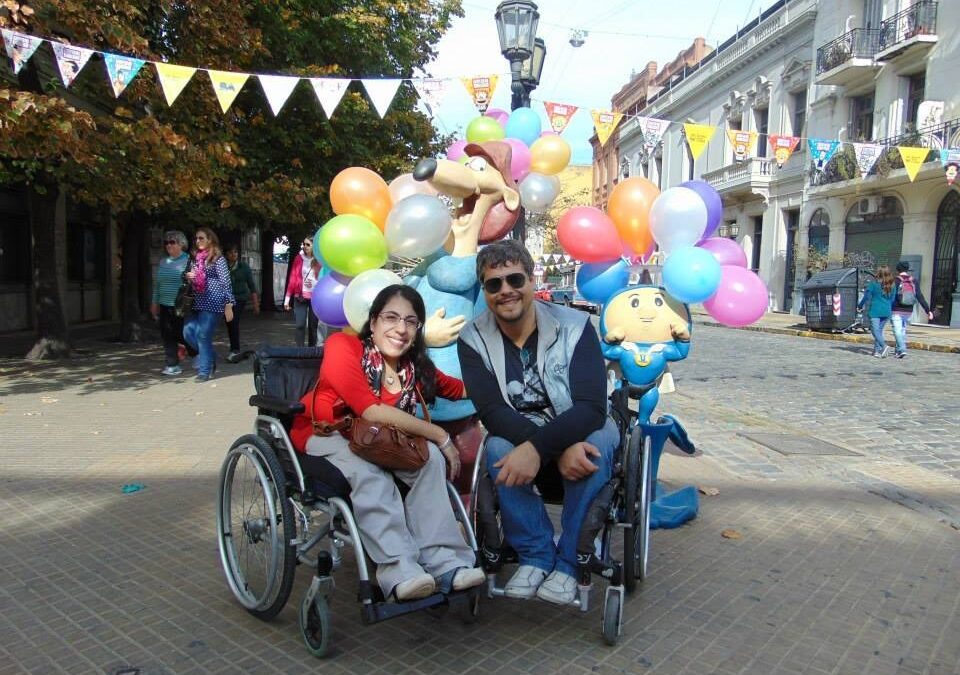 Daiana y Julián en una calle de San Telmo, detras de ellos, esculturas de Larguirucho y Super Hijitus con globos de colores.